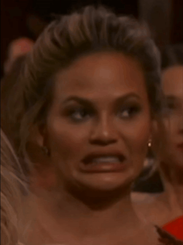 A woman makes a strained, uncomfortable grimace.
