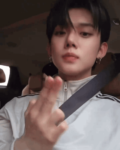 a young man wearing a seat belt is making a heart shape with his hands