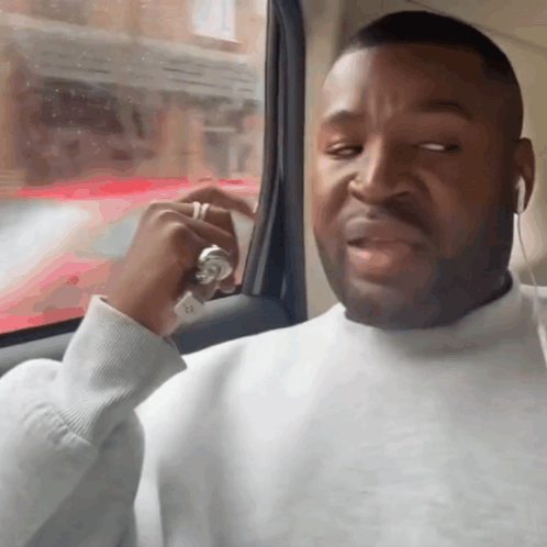 A man in a white shirt gives a judging side-eye from a car.