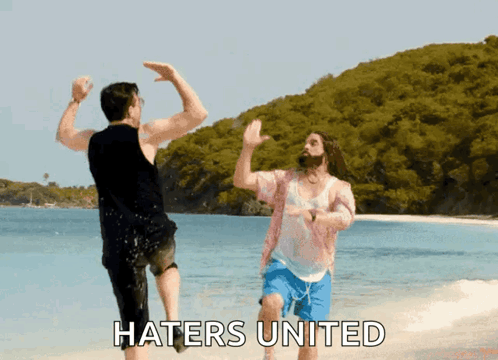 Two people splash in shallow water and raise their hands for a high five under “HATERS UNITED.”