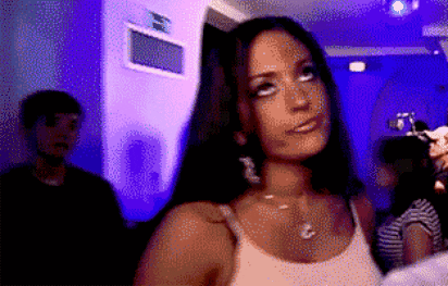 A woman in a nightlife setting rolls her eyes dismissively.