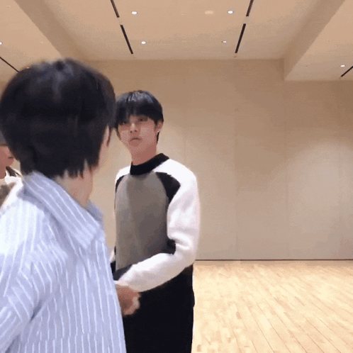two men standing next to each other in a room