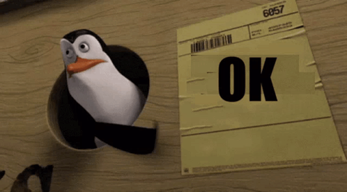 A penguin stands beside a cardboard box labeled “OK.”