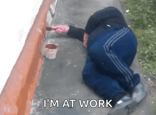 A person crouches near a curb with the caption “I’M AT WORK.”