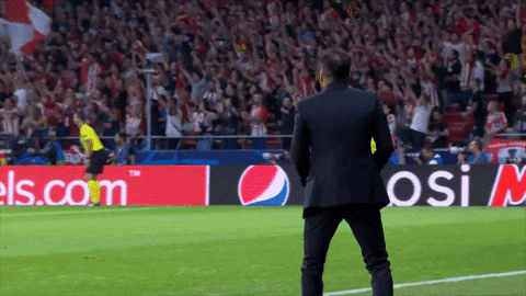a man in a suit stands on a soccer field in front of an advertisement for pepsi