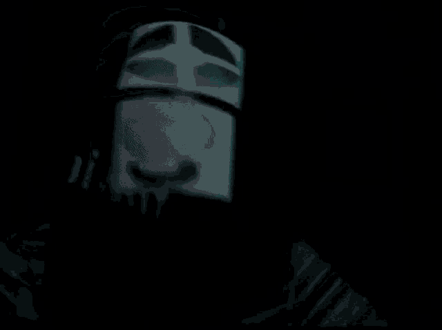 a person wearing a mask with a skull on it is standing in a dark room .