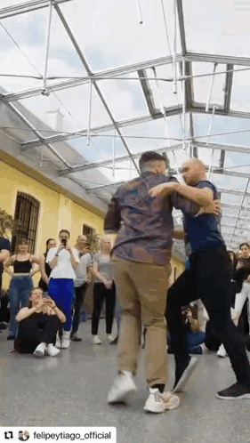 a group of people are dancing in a room with a clear roof .