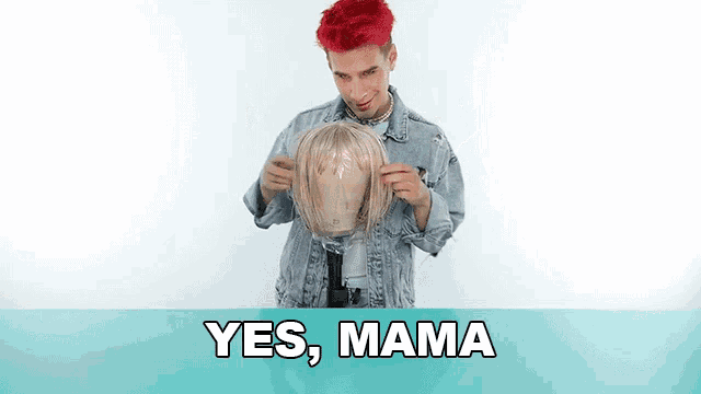 a man with red hair is holding a wig in his hands and says yes mama .