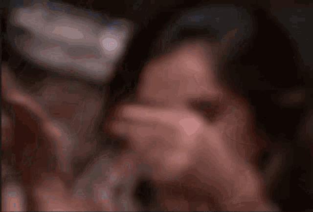 a blurry picture of a woman covering her face with her hand .