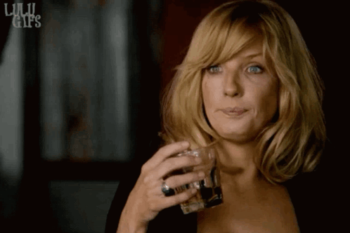Beth Dutton holds a drink and gives a small knowing shrug.
