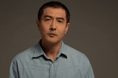A man speaks directly to camera with a serious expression.