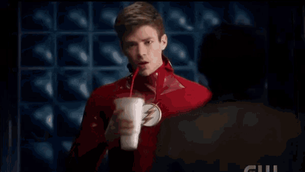 a man in a flash costume is holding a drink and says yes
