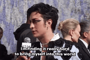 a man is holding a microphone and saying i 'm finding it really hard to bring myself into this world