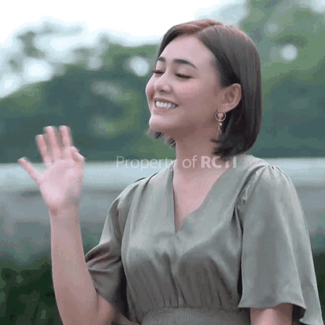 a woman in a green dress is waving her hand in front of a property of rc logo