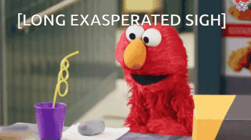 Elmo sits at a table making a long exasperated sigh.