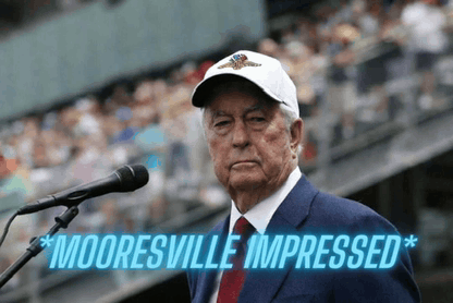a man in a suit stands in front of a microphone with the words mooresville impressed behind him