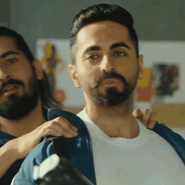 a man with a beard is being helped into a jacket