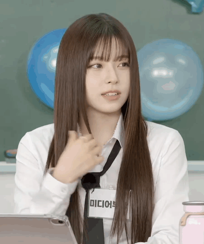 Kyujin from NMIXX gestures toward herself in front of blue balloons.