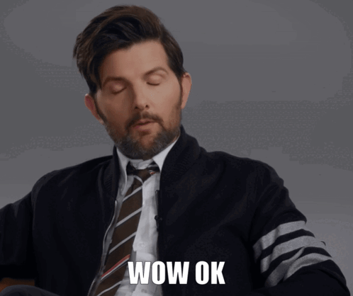 A man in a suit closes his eyes in a resigned “WOW OK” reaction.