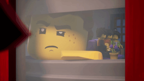 a lego head with a sad look on his face is behind a red curtain
