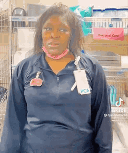 A tired worker in a dark uniform stares ahead in a store aisle.