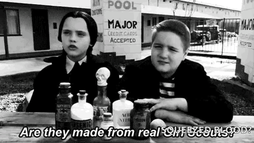 a black and white photo of two boys sitting at a table with bottles .