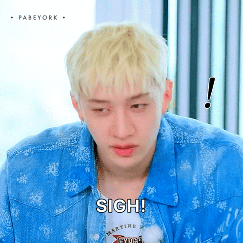 a man with blonde hair is wearing a blue shirt with the word sigh on it