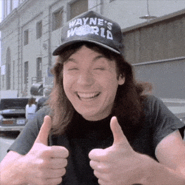 A smiling person in a “Wayne's World” hat gives double thumbs-up.