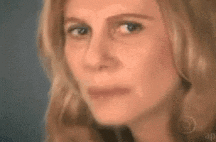 A woman looks off-camera with a calculating, doubtful expression.
