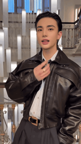 a young man wearing a leather jacket and tie is standing in front of a staircase