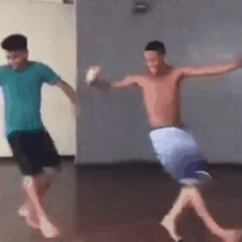 two shirtless men are dancing in a room .