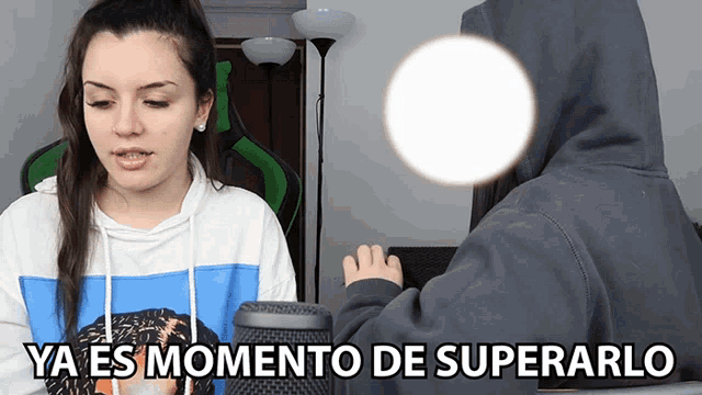 a woman in a blue and white hoodie stands next to a man in a gray hoodie with the words ya es momento de superarlo
