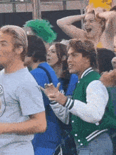 A man in a crowd gives a thumbs up outdoors.