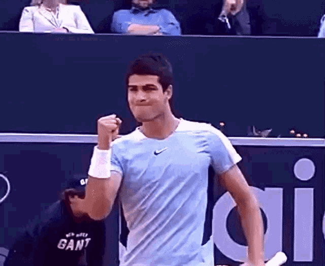 a man in a blue shirt is holding a tennis racquet in his hand