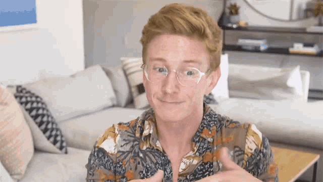 a man wearing glasses and a colorful shirt is sitting on a couch