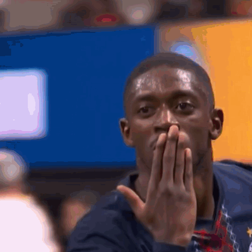 a man covering his mouth with his hands in front of a television