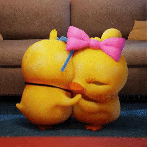 two yellow ducks with pink bows on their heads are hugging each other in front of a couch