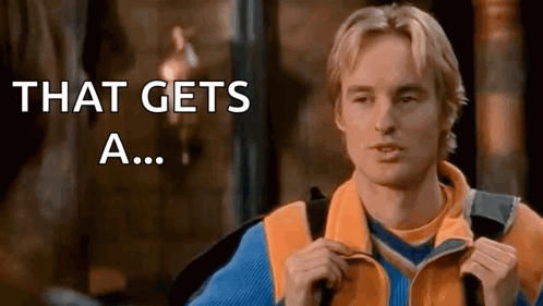 Owen Wilson gestures toward himself as text says “THAT GETS A...”