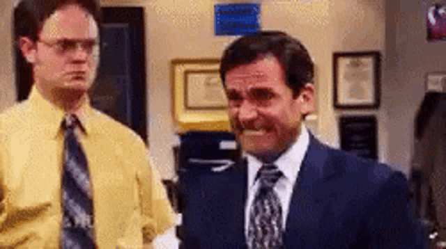 Two men in an office exchange a tense, uncertain look.