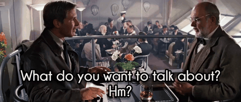 two men are sitting at a table and one of them is asking the other what do you want to talk about