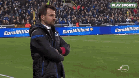 a man stands on a soccer field in front of a euromillions sign