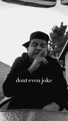 a man sitting at a table with his finger in his mouth and the words dont even joke above him