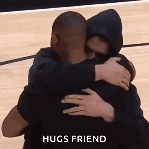 Two men warmly hug with the caption “HUGS FRIEND.”