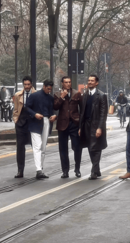 a group of men are walking down a street and one of them is wearing a blue shirt