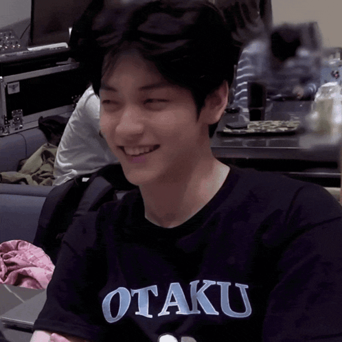 a young man wearing a black shirt that says otaku smiles