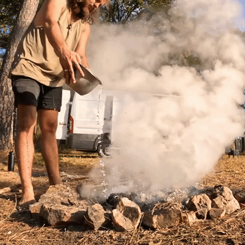 a man pouring water into a fire with smoke coming out