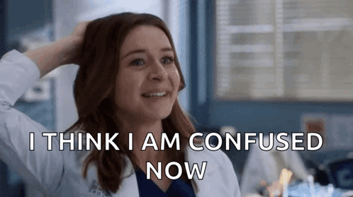 a woman in a lab coat is smiling and scratching her head while saying i think i am confused now .