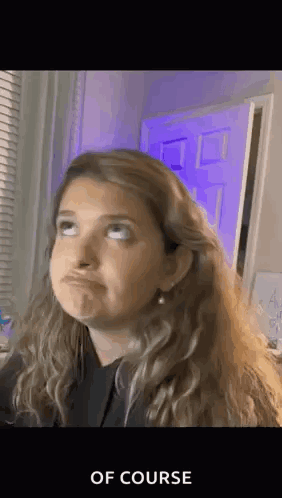 a woman is making a funny face in front of a purple door and a window .