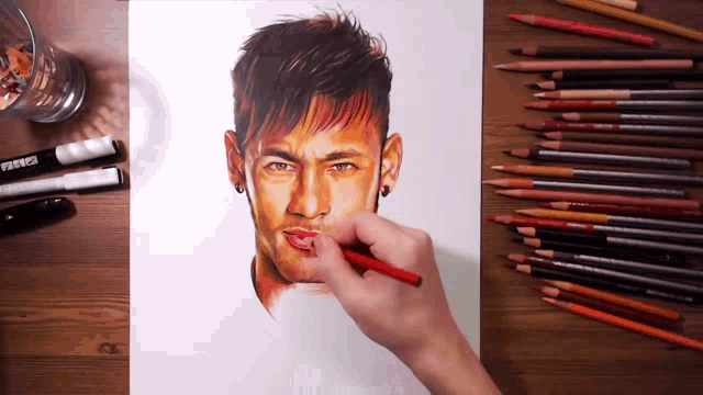 a person is drawing a man 's face with colored pencils on a wooden table