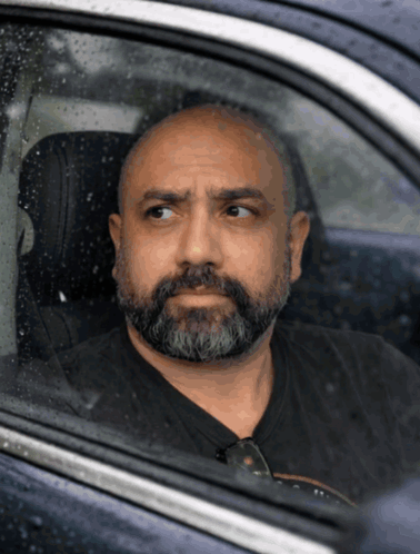 Man in a car stares forward with a guilty, uneasy expression.